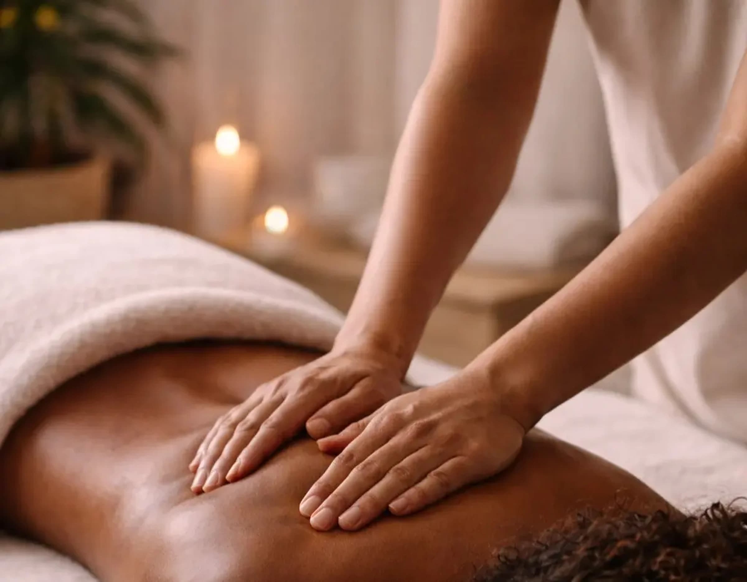 A calm hands-on massage in a softly lit treatment room.